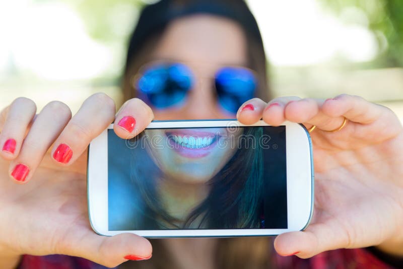 Stående av den härliga flickan som tar en selfie med mobiltelefonen arkivbild Stående av den härliga flickan som tar en selfie med mobiltelefonen arkivbild