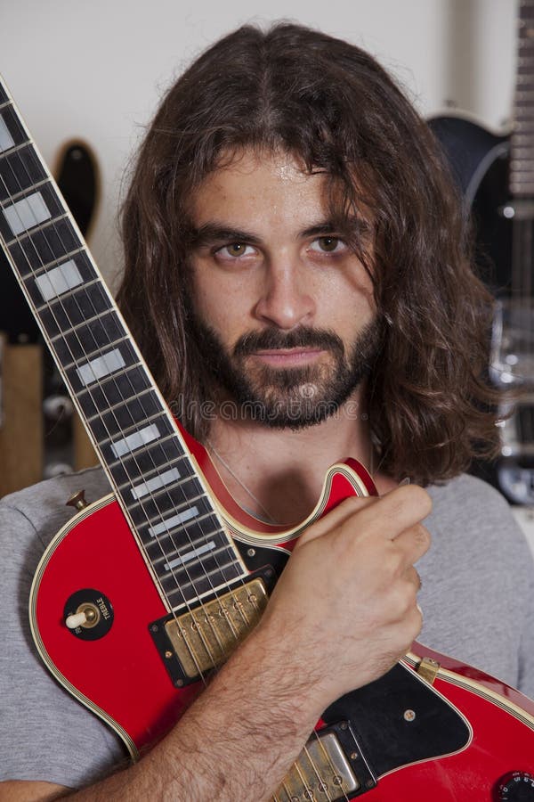 Stående av den hållande gitarren för allvarlig ung musiker fotografering för bildbyråer