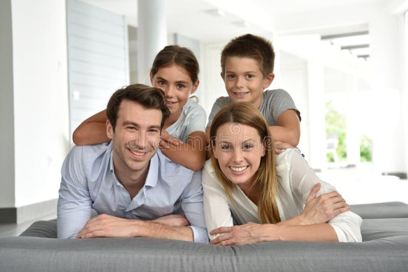 Stående av den lyckliga familjen som ligger på kopplad av soffakänsla arkivfoton Stående av den lyckliga familjen som ligger på kopplad av soffakänsla arkivfoton