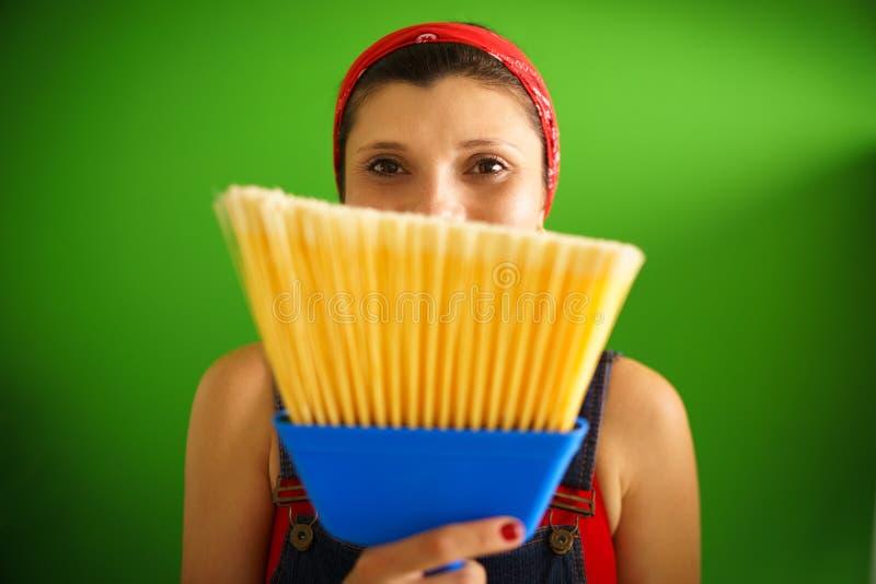 Happy young hispanic woman at home, doing chores and housekeeping, smiling at camera behind yellow broom. Happy young hispanic woman at home, doing chores and housekeeping, smiling at camera behind yellow broom