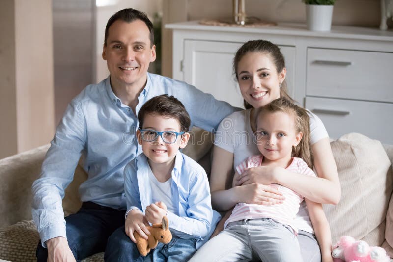 Stående av den lyckliga unga familjen av fyra som poserar för bild royaltyfria bilder Stående av den lyckliga unga familjen av fyra som poserar för bild royaltyfria bilder