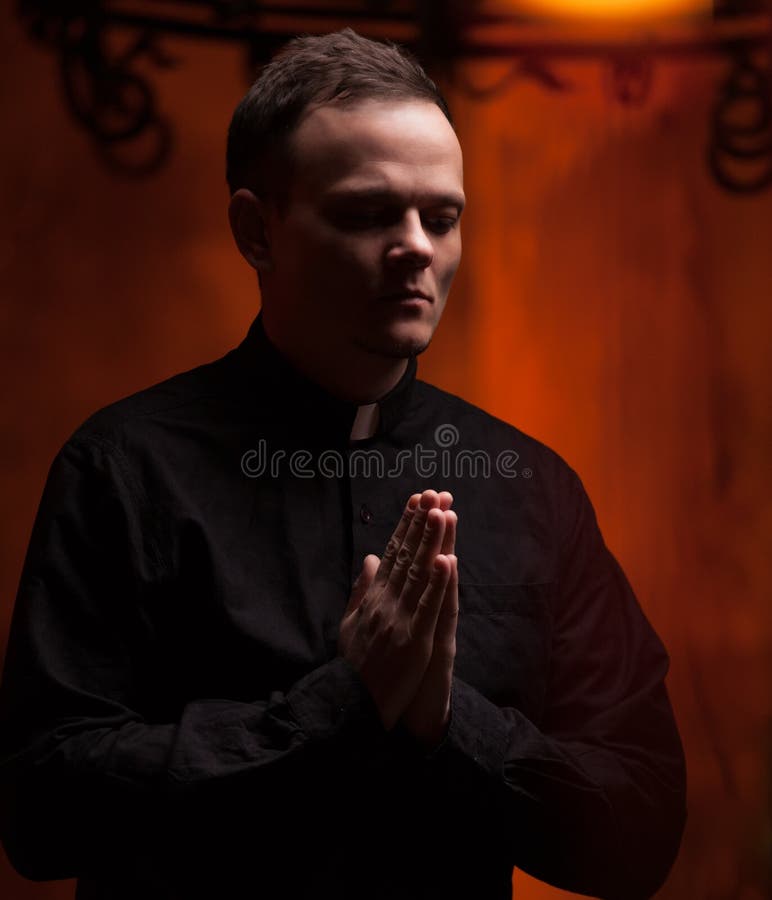 Stående av den stiliga katolska prästen eller pastorn med hundhalsbandet, mörker - röd bakgrund fotografering för bildbyråer Stående av den stiliga katolska prästen eller pastorn med hundhalsbandet, mörker - röd bakgrund fotografering för bildbyråer