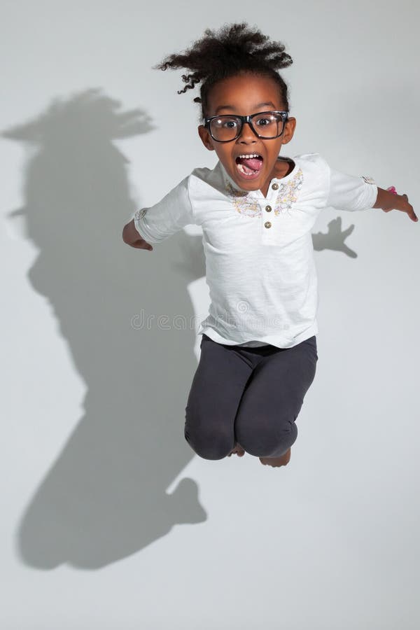 Portrait of cute Young African American girl jumping, over gray background. Portrait of cute Young African American girl jumping, over gray background