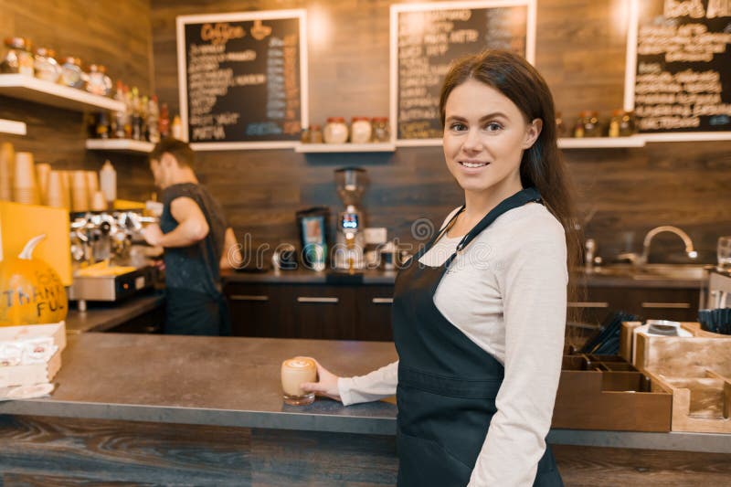 Stående av den unga kvinnliga små och medelstora företagägaren - liten modern coffee shop, säkert kvinnaanseende på räknaren med arkivfoto Stående av den unga kvinnliga små och medelstora företagägaren - liten modern coffee shop, säkert kvinnaanseende på räknaren med arkivfoto