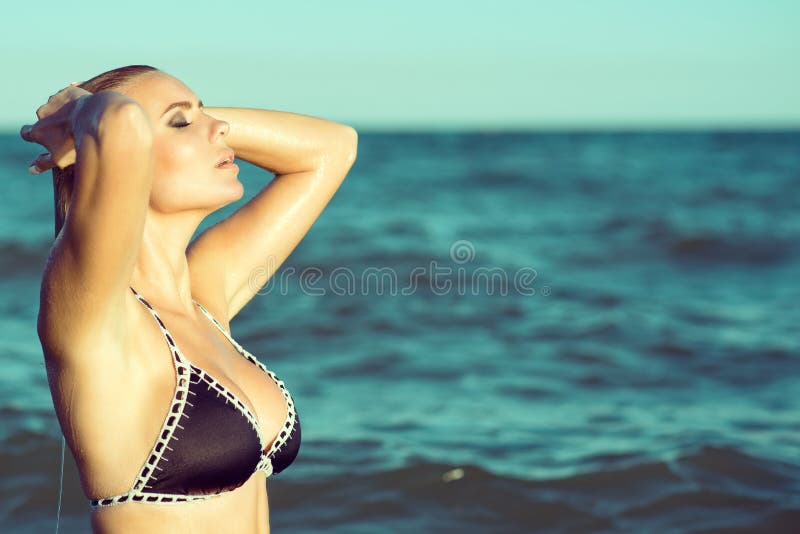 Stående av den ursnygga blonda kvinnan i baddräkten som kommer upp från havet med stängda ögon och gör slät hennes våta hår royaltyfri fotografi Stående av den ursnygga blonda kvinnan i baddräkten som kommer upp från havet med stängda ögon och gör slät hennes våta hår royaltyfri fotografi