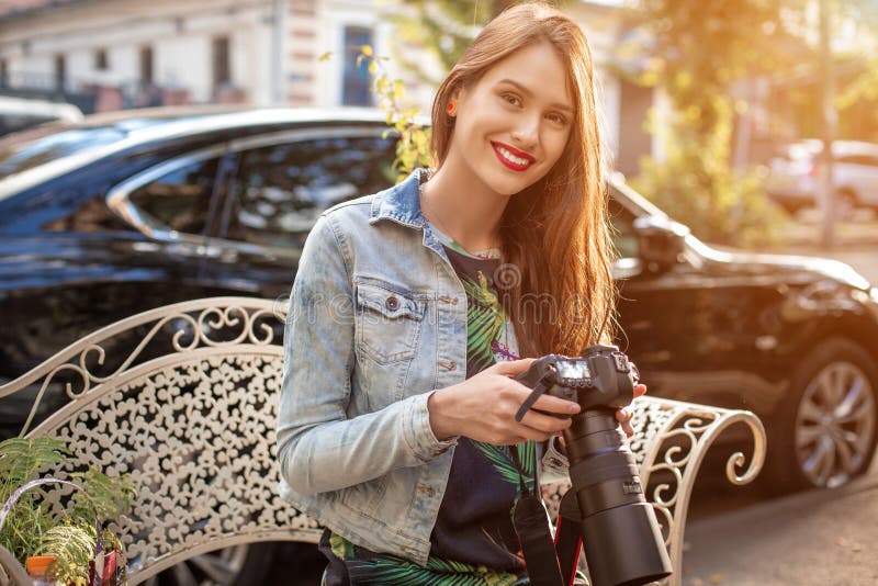 Stående av den yrkesmässiga kvinnliga fotografen på gatan som fotograferar på en kamera royaltyfri bild Stående av den yrkesmässiga kvinnliga fotografen på gatan som fotograferar på en kamera royaltyfri bild