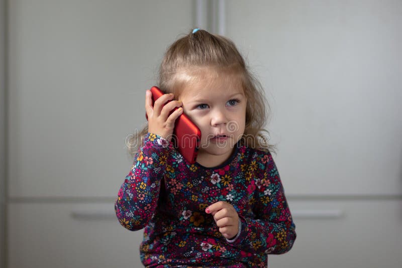 Stående av det gulliga och attraktiva barnet som talar på mobiltelefonen som åt sidan ser arkivbild