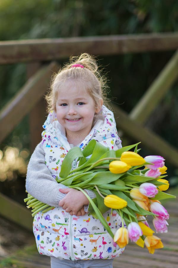 Stående av en blond flicka med en bukett av tulpan i hennes händer royaltyfri fotografi Stående av en blond flicka med en bukett av tulpan i hennes händer royaltyfri fotografi