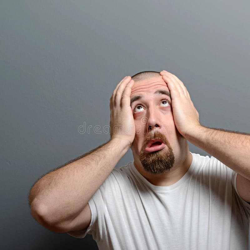 Stående av en desperat man i chock mot grå bakgrund arkivfoto Stående av en desperat man i chock mot grå bakgrund arkivfoto