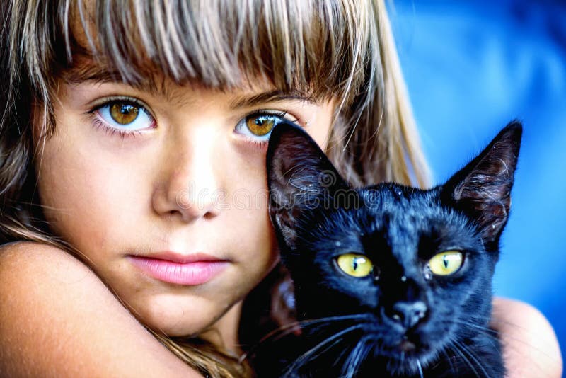 Stående av en härlig liten flicka som rymmer en svart katt royaltyfria foton Stående av en härlig liten flicka som rymmer en svart katt royaltyfria foton