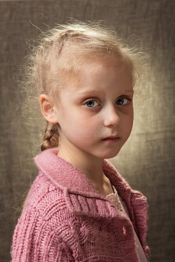 Stående av en liten ljus ledsen flicka på en ljus bakgrund arkivbilder Stående av en liten ljus ledsen flicka på en ljus bakgrund arkivbilder