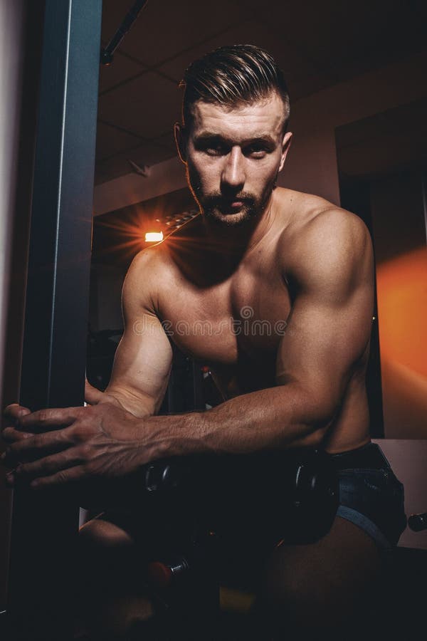 Stående av en mycket muskulös shirtless manlig modell Stilig idrotts- man med stora muskler som poserar på kameran i idrottshalle royaltyfria foton Stående av en mycket muskulös shirtless manlig modell Stilig idrotts- man med stora muskler som poserar på kameran i idrottshalle royaltyfria foton