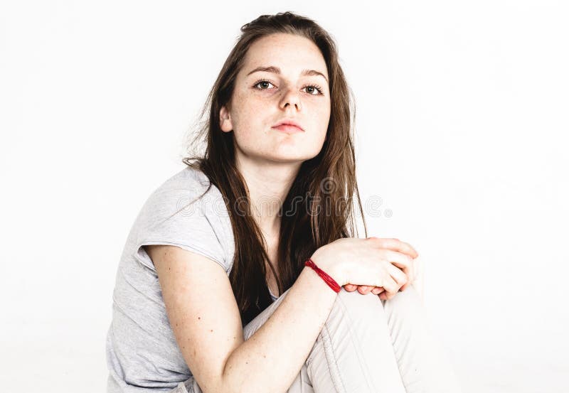 Stående av ett nätt flickasammanträde för ung kvinna på golvet som isoleras på vit royaltyfri bild Stående av ett nätt flickasammanträde för ung kvinna på golvet som isoleras på vit royaltyfri bild