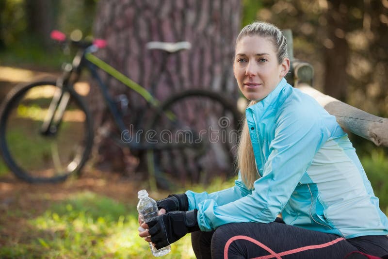 Stående av flaskan för vatten för kvinnlig bergcyklist den hållande royaltyfri fotografi Stående av flaskan för vatten för kvinnlig bergcyklist den hållande royaltyfri fotografi
