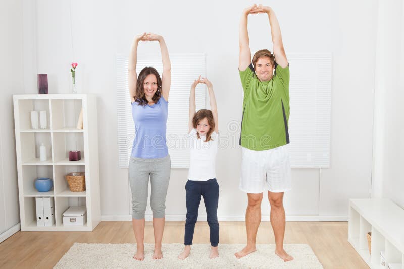 Stående av passformfamiljen som utför yoga royaltyfri bild Stående av passformfamiljen som utför yoga royaltyfri bild