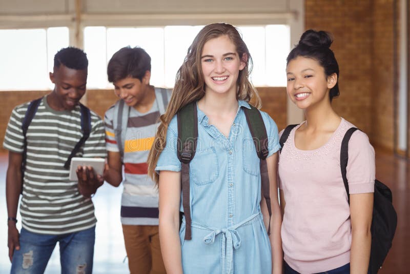 Stående av skolflickor som står med klasskompisen med klasskompisar i bakgrund