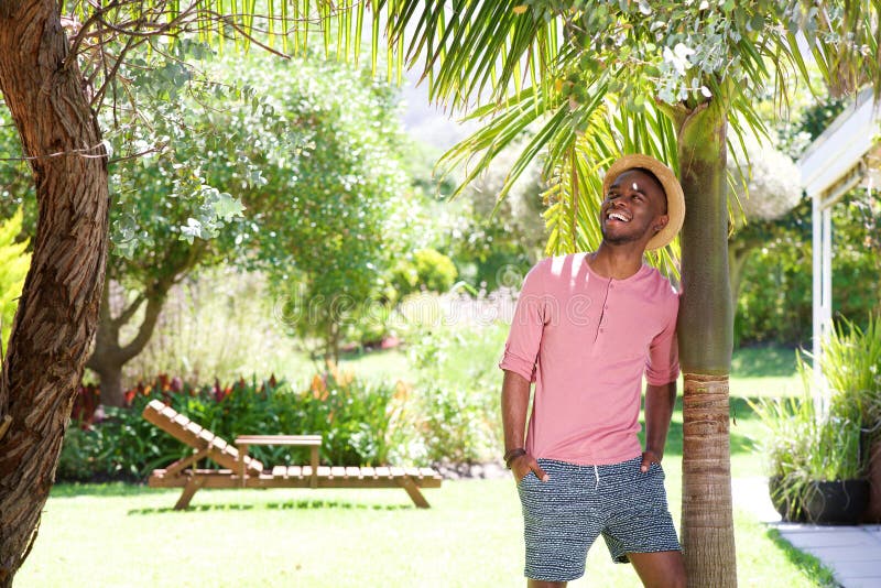 Portrait of happy young african man leaning to a tree outdoors on a summer day. Portrait of happy young african man leaning to a tree outdoors on a summer day