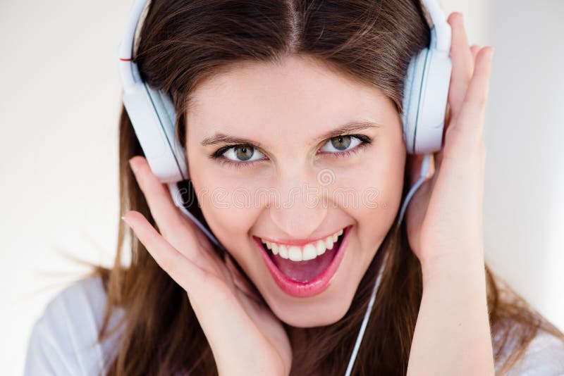 Stående hörlurar och entusiastisk kvinna som lyssnar på musik eller låt isolerad på vit studions bakgrund. ansikte arkivbild