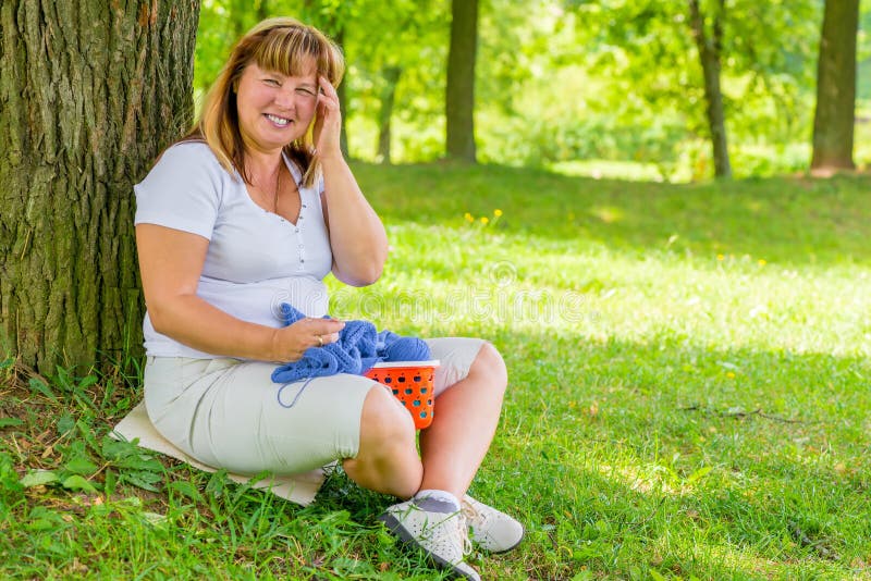 Portrait laughing 50 year old woman in the park dedicated to knitting. Portrait laughing 50 year old woman in the park dedicated to knitting