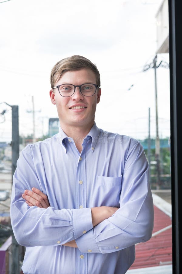 Ståenden av affärsmannen med armar korsade på kontoret ung man s arkivfoto Ståenden av affärsmannen med armar korsade på kontoret ung man s arkivfoto