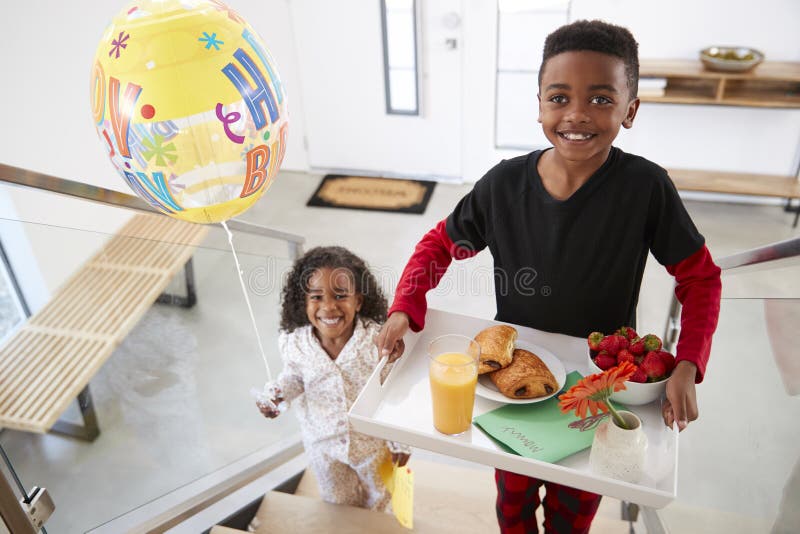 Ståenden av barn som kommer med föräldrar, frukosterar i säng på den Tray With Balloon To Celebrate födelsedagen royaltyfria foton Ståenden av barn som kommer med föräldrar, frukosterar i säng på den Tray With Balloon To Celebrate födelsedagen royaltyfria foton