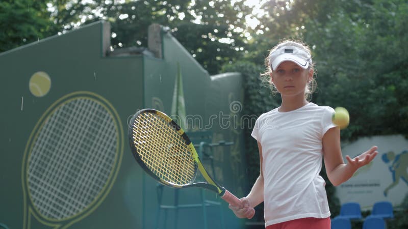 Ståenden av den allvarliga tennisspelaren för den tonårs- flickan med racket i hand och kast klumpa ihop sig i sportar klubbar ut