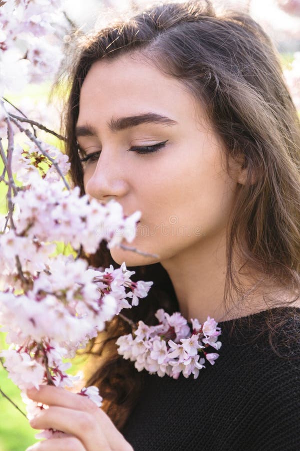 Ståenden av den härliga flickan sniffar blomma filialen fotografering för bildbyråer Ståenden av den härliga flickan sniffar blomma filialen fotografering för bildbyråer
