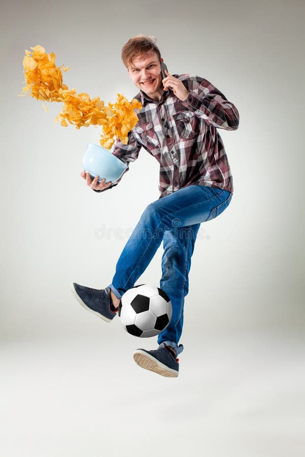 Ståenden av den unga mannen med den smarta telefonen och fotboll klumpa ihop sig royaltyfri bild Ståenden av den unga mannen med den smarta telefonen och fotboll klumpa ihop sig royaltyfri bild