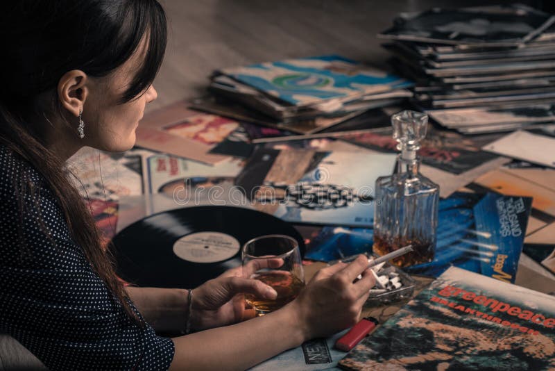 Ståenden av en härlig flicka, glass whisky som lyssnar till musik från vinylLP, antecknar tappning arkivbild Ståenden av en härlig flicka, glass whisky som lyssnar till musik från vinylLP, antecknar tappning arkivbild