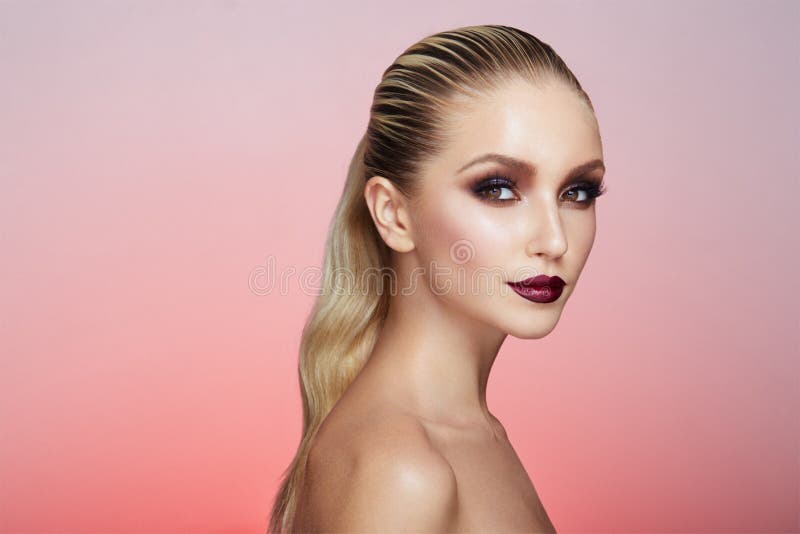 Ståenden av kvinnan med storartad makeup och hår rätade ut och fångade i baksidan som isolerades på en rosa bakgrund arkivbilder Ståenden av kvinnan med storartad makeup och hår rätade ut och fångade i baksidan som isolerades på en rosa bakgrund arkivbilder