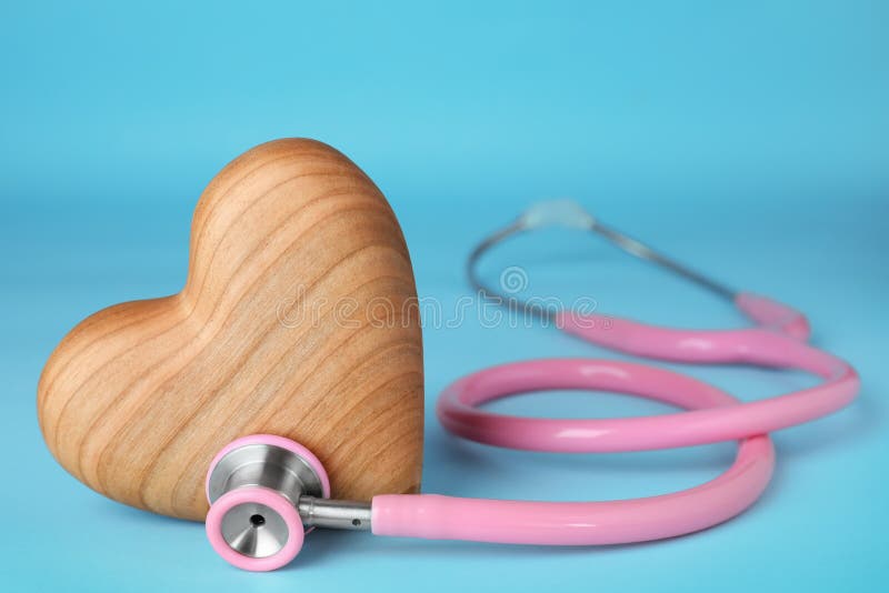 Stéthoscope avec le coeur en bois sur le fond bleu, plan rapproché photographie stock Stéthoscope avec le coeur en bois sur le fond bleu, plan rapproché photographie stock