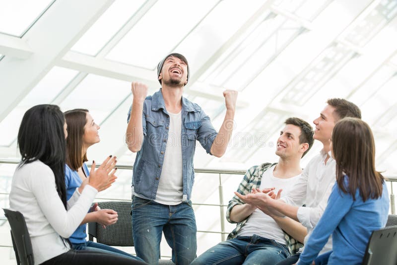 Young men is sharing his problems with people. View of men is telling something and gesturing while group of people are sitting in front of him and listening. Young men is sharing his problems with people. View of men is telling something and gesturing while group of people are sitting in front of him and listening.