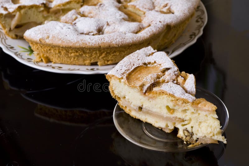 One piece of fruit pie on a saucer, the whole pie is on background. On dark background. One piece of fruit pie on a saucer, the whole pie is on background. On dark background.