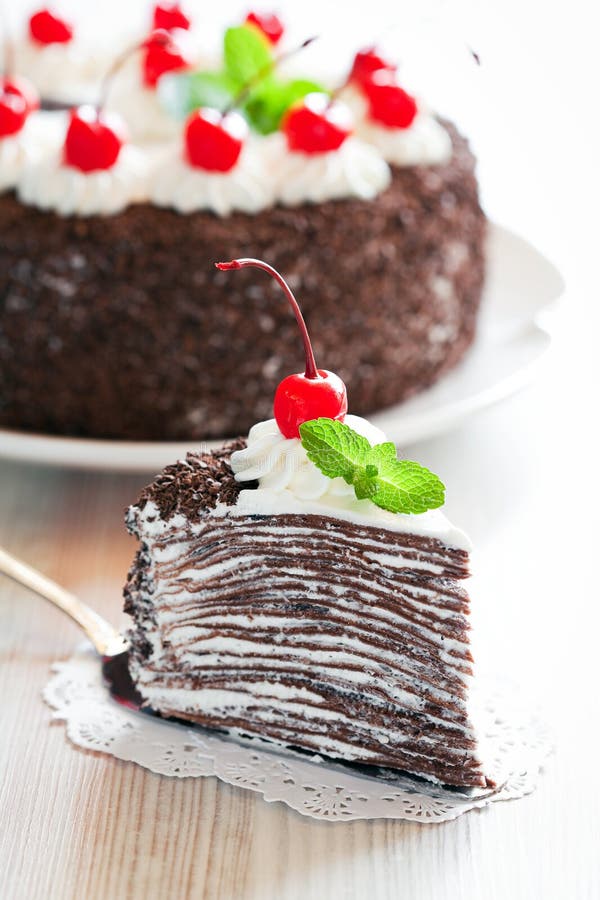 Piece of chocolate crepe cake with whipped cream and glazed cherries, selective focus. Piece of chocolate crepe cake with whipped cream and glazed cherries, selective focus