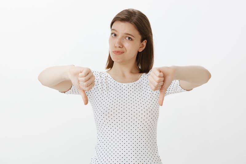 Su idea chupa Retrato de la mujer europea linda descontentada poco impresionada en camiseta de moda, mostrando los pulgares abajo imagen de archivo Su idea chupa Retrato de la mujer europea linda descontentada poco impresionada en camiseta de moda, mostrando los pulgares abajo imagen de archivo