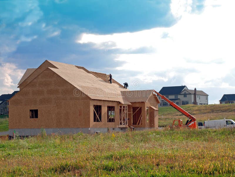 The wood frame of a future luxury home surrounded by colorful fields. The wood frame of a future luxury home surrounded by colorful fields.