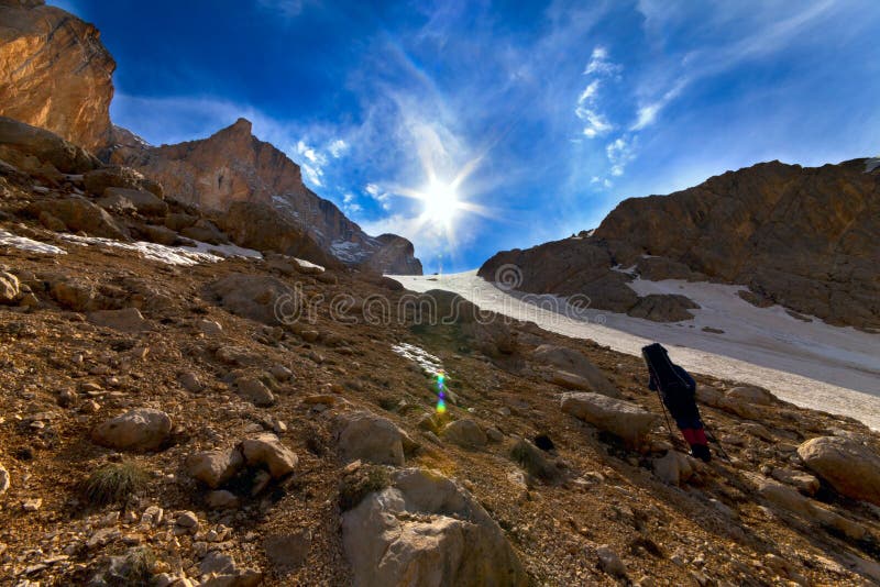Subida cansada del caminante al paso de montaña por la tarde imagen de archivo libre de regalías Subida cansada del caminante al paso de montaña por la tarde imagen de archivo libre de regalías