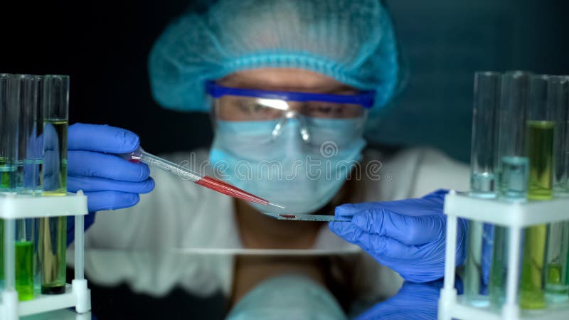 Subst?ncia alaranjada do gotejamento do pesquisador no vidro do teste, estudando propriedades l?quidas imagens de stock Subst?ncia alaranjada do gotejamento do pesquisador no vidro do teste, estudando propriedades l?quidas imagens de stock