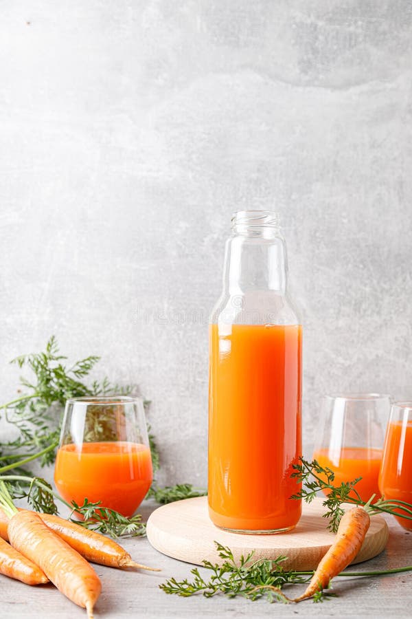 Suc de morcovi în sticlă și sticlă și morcovi proaspeți cu frunze stock image