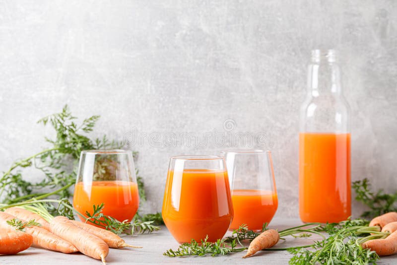 Suc de morcovi în sticlă și sticlă și morcovi proaspeți cu frunze stock photography