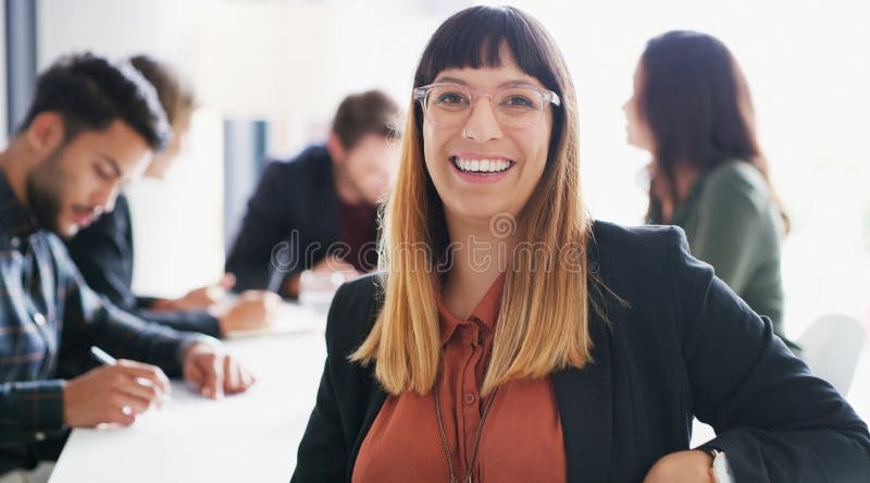 Success requires every effort of yours. Portrait of a young businesswoman sitting in an office with her colleagues in stock photography