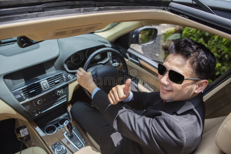 Successful businessman shows OK sign in the car