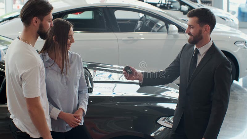 Successful deal between car salesman and young couple in car dealership. royalty free stock images Successful deal between car salesman and young couple in car dealership. royalty free stock images