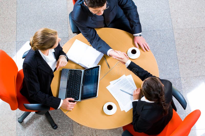 Confident business partners sitting at the table and shaking hands. Negotiating table stock images, royalty-free photos and pictures