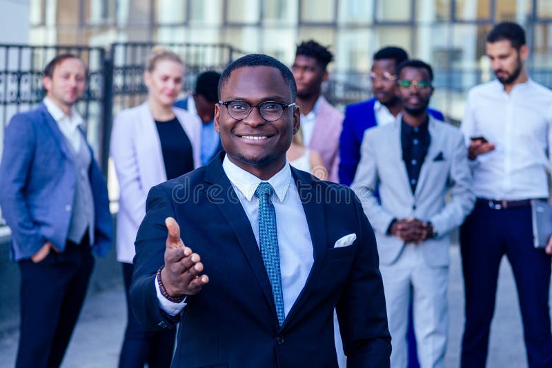 Successful and handsome African American man in a stylish business suit giving a hand for a handshake sign welcome ahead