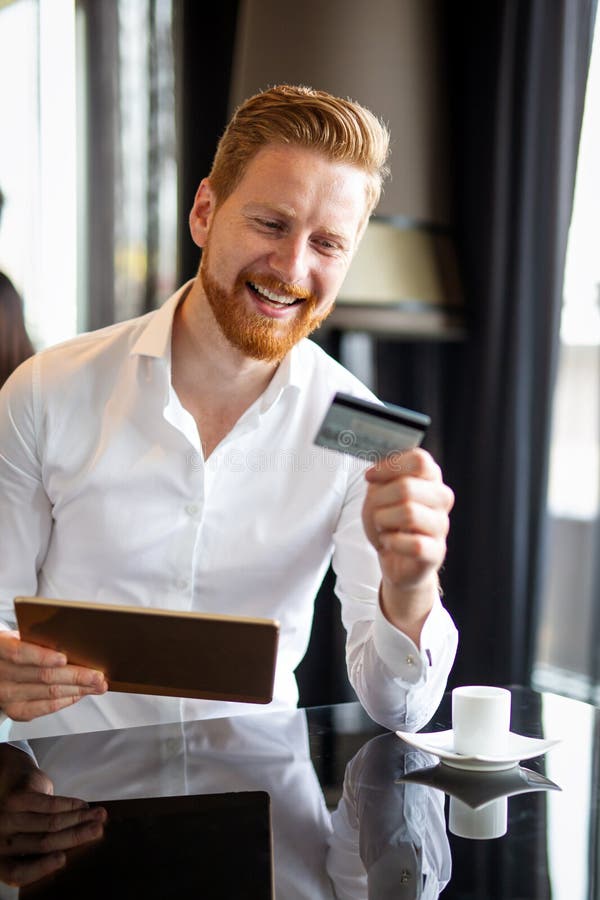 Successful handsome business man holding credit card, using digital tablet. Online shopping concept royalty free stock photo