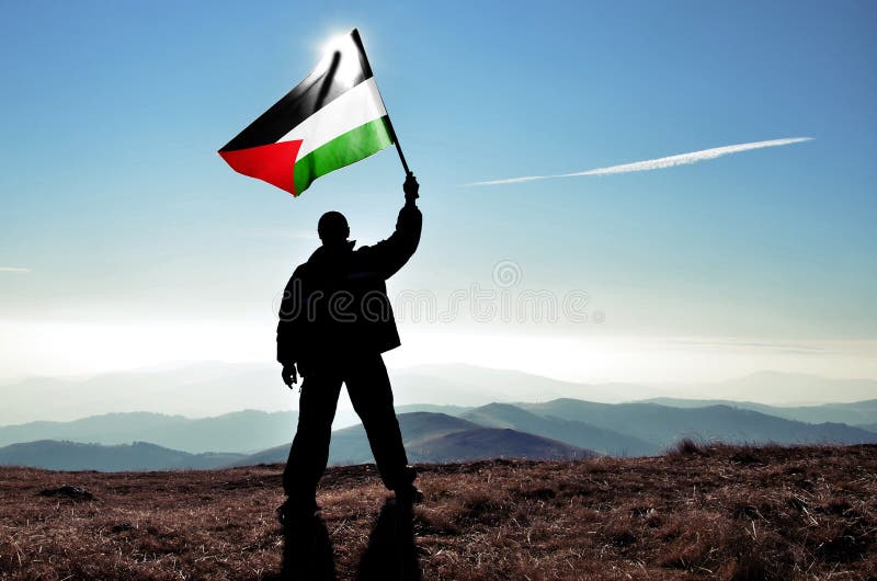 Successful silhouette man winner waving Palestine flag on top of the mountai. N peak royalty free stock image