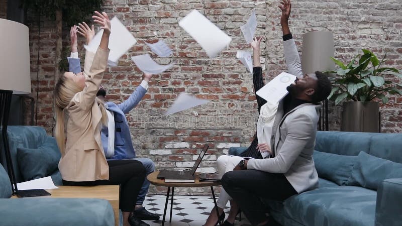 Succesvol gevarieerd team van zakenmensen die werkdocumenten opgooien, vieren het succes van bedrijven en de overwinning in gezam