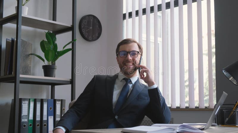 Succesvolle aantrekkelijke verkoopmanager die aan de telefoon terwijl het zitten in een comfortabele stoel spreekt.