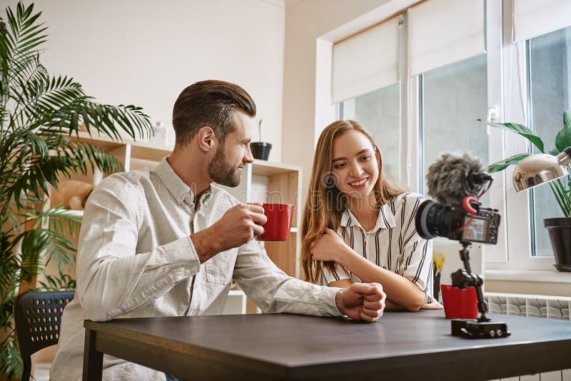 Succesvolle bloggers Het glimlachen bloggers die een thee drinken terwijl het maken van nieuwe inhoud voor hun blog stock afbeelding Succesvolle bloggers Het glimlachen bloggers die een thee drinken terwijl het maken van nieuwe inhoud voor hun blog stock afbeelding